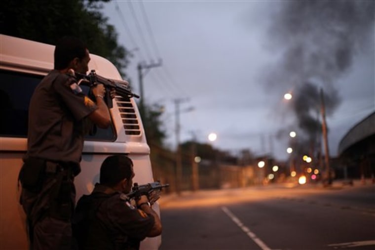 Police officers aim their weapons Wednesday during riots at Jacarezinho slum in Rio de Janeiro, Brazil.